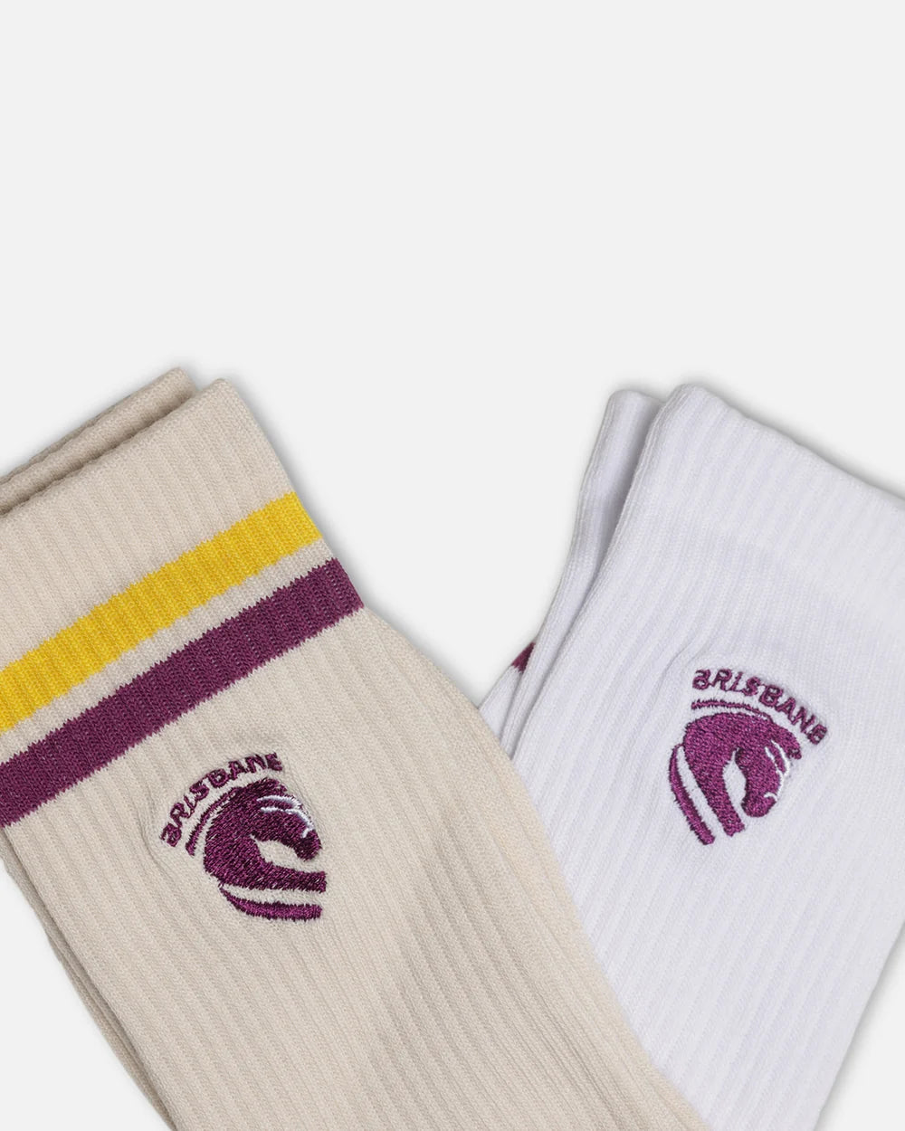 Two ribbed crew socks shown on a light gray background. One sock is cream with yellow and dark purple stripes and a dark purple Brisbane horse logo, and the other is white with a matching dark purple Brisbane horse logo.