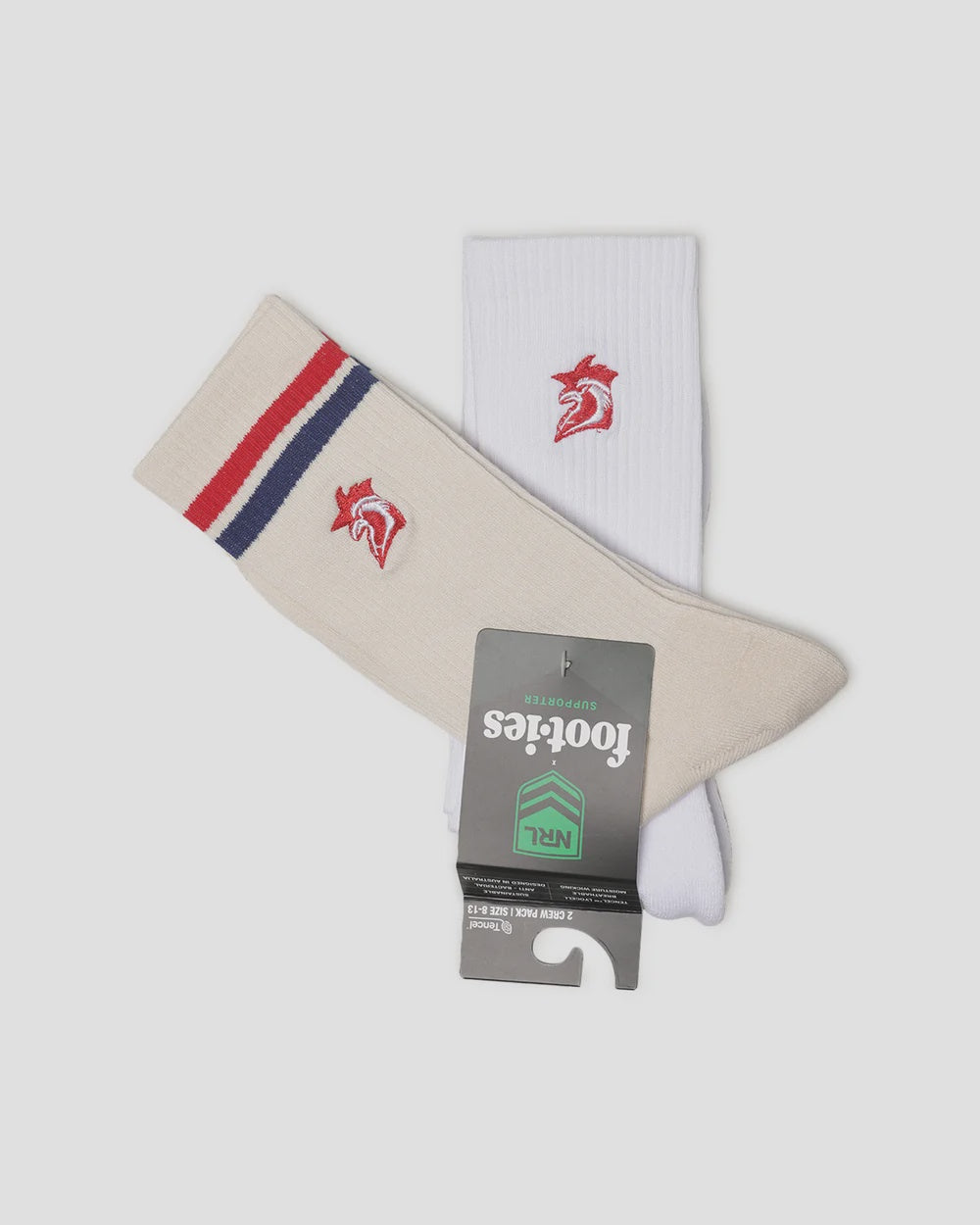 A pair of Footies brand crew socks, one cream and one white, featuring red and navy stripes on the cuff and a red horse logo. A grey hangtag is attached to the cream sock.