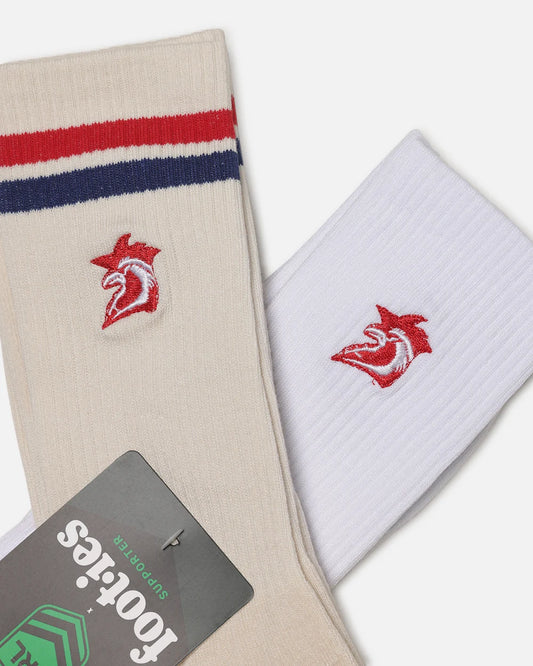 Two pairs of crew socks displayed diagonally on a light gray background. One pair is cream/beige with red and navy blue stripes near the cuff and a red and white bird logo embroidered on the front.