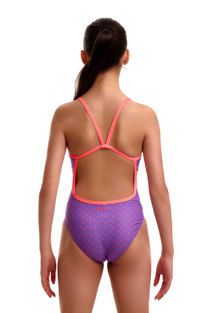 Back view of a young girl wearing the Funkita Single Strap swimsuit in purple with an orange plus/cross pattern, showing thin peach single-bind straps, an open back cutout, and the orange 'FUNKITA' logo across the lower back.