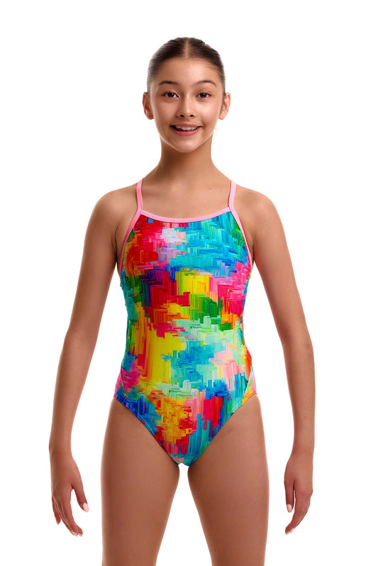 Front view of a young girl wearing the Funkita Twisted one-piece swimsuit featuring a bright, colorful abstract paint-splatter pattern in red, yellow, blue, and green with thin pink shoulder straps.