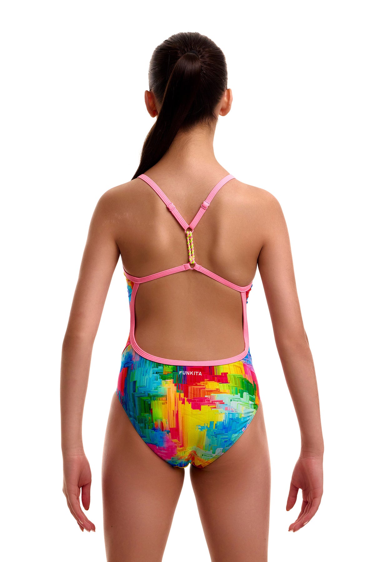 Back view of a young girl wearing the Funkita Twisted swimsuit in a colorful abstract paint-splatter print, showing pink single-bind shoulder straps that converge and twist at the upper back, an open back cutout, and the white 'FUNKITA' logo across the lower back.