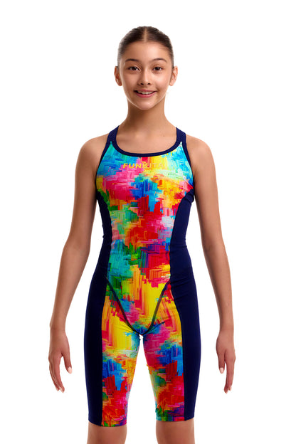 Front view of a young girl wearing the Funkita Girls Fast Training knee-length legsuit swimsuit featuring a colorful paint-splatter front panel in red, yellow, and blue with navy side panels.