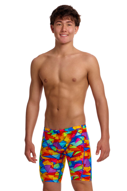 A young male model standing against a white background wearing the Funky Trunks "Try The Lot" Boys Training Jammers, featuring a bright, multi-colored geometric pattern with red, yellow, blue, and green