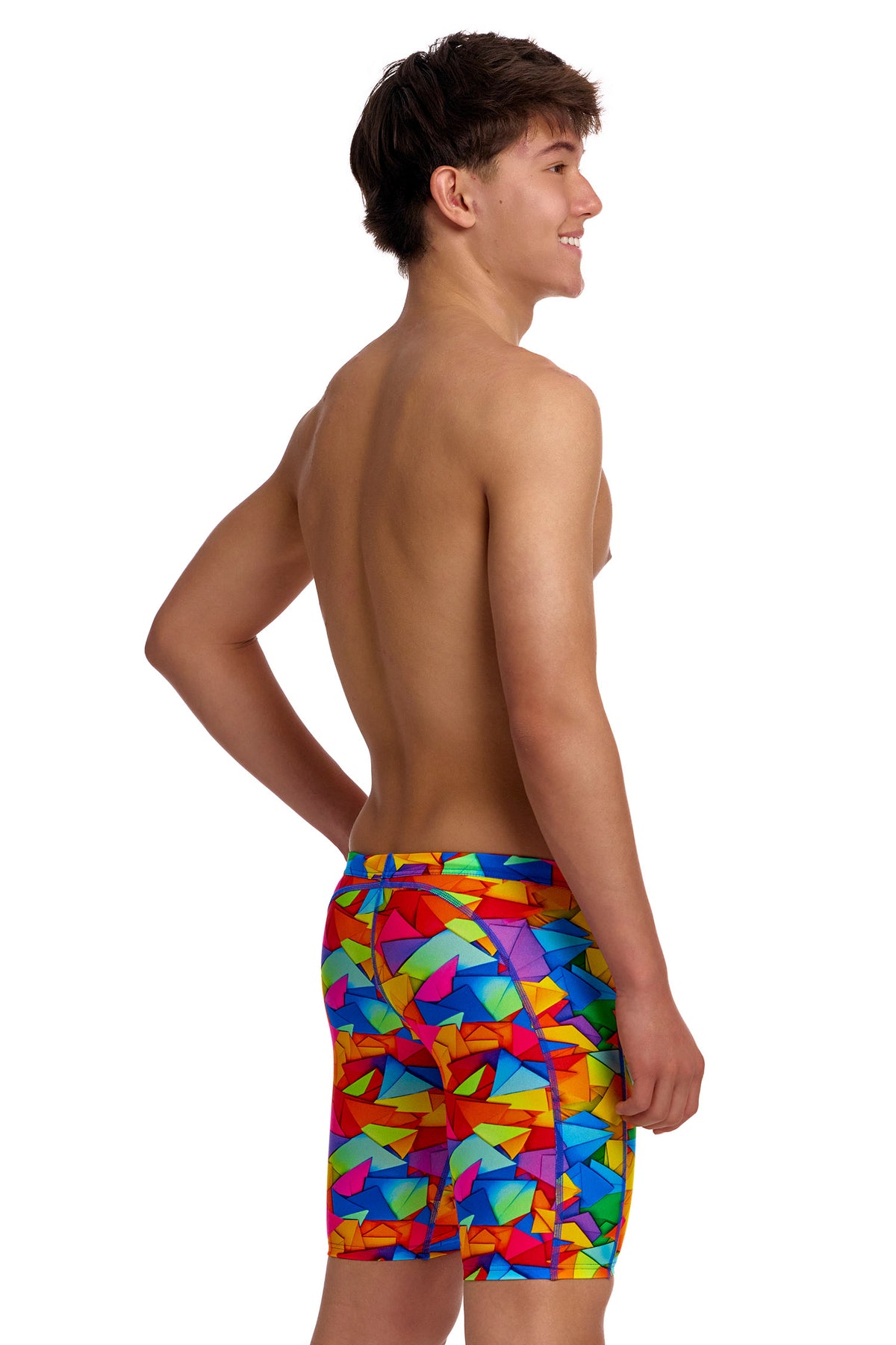 A young male model standing against a white background wearing the Funky Trunks "Try The Lot" Boys Training Jammers, featuring a bright, multi-colored geometric pattern with red, yellow, blue, and green