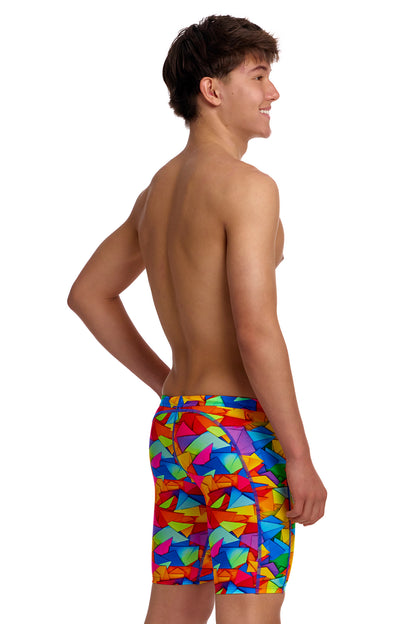 A young male model standing against a white background wearing the Funky Trunks "Try The Lot" Boys Training Jammers, featuring a bright, multi-colored geometric pattern with red, yellow, blue, and green