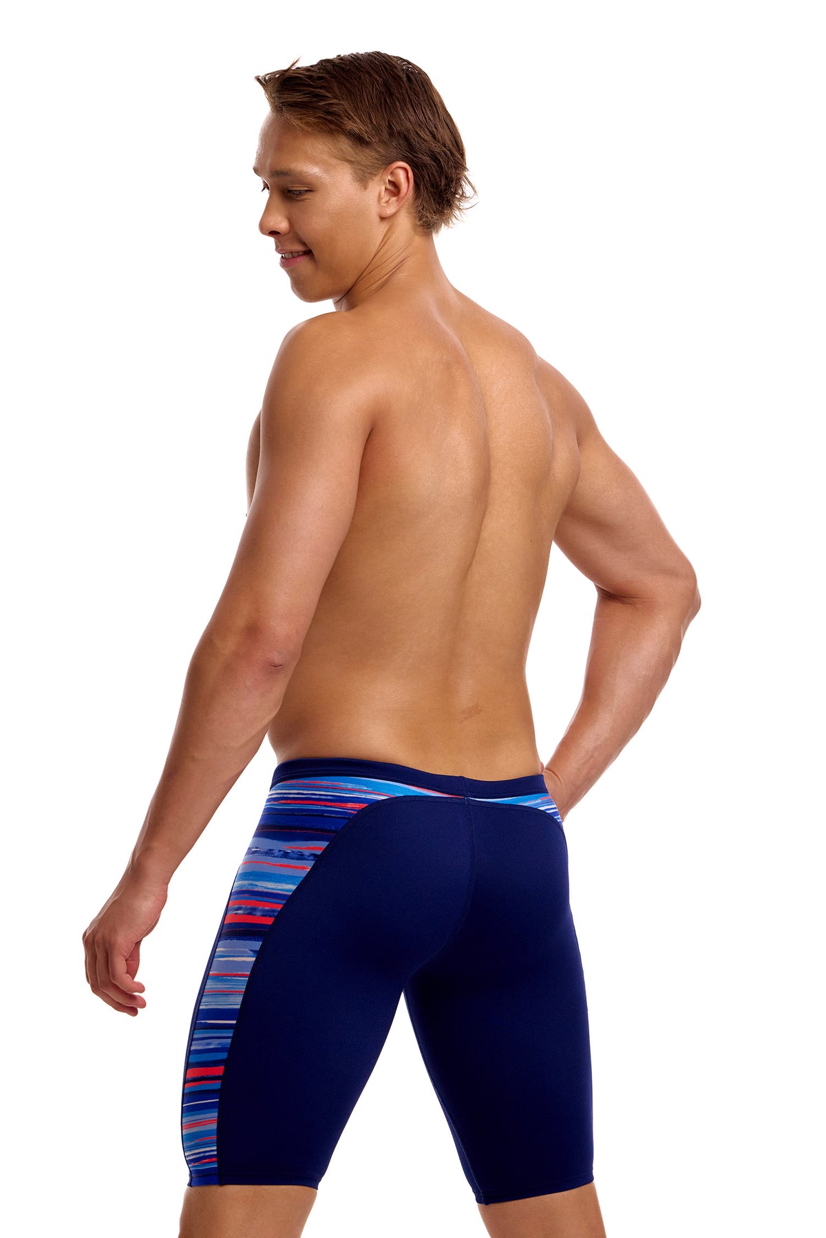 A male athlete standing against a white background modeling the Funky Trunks "Lost Lines" Men's Swim Jammers, featuring a dark navy body with a colorful, multi-striped accent panel along the side.