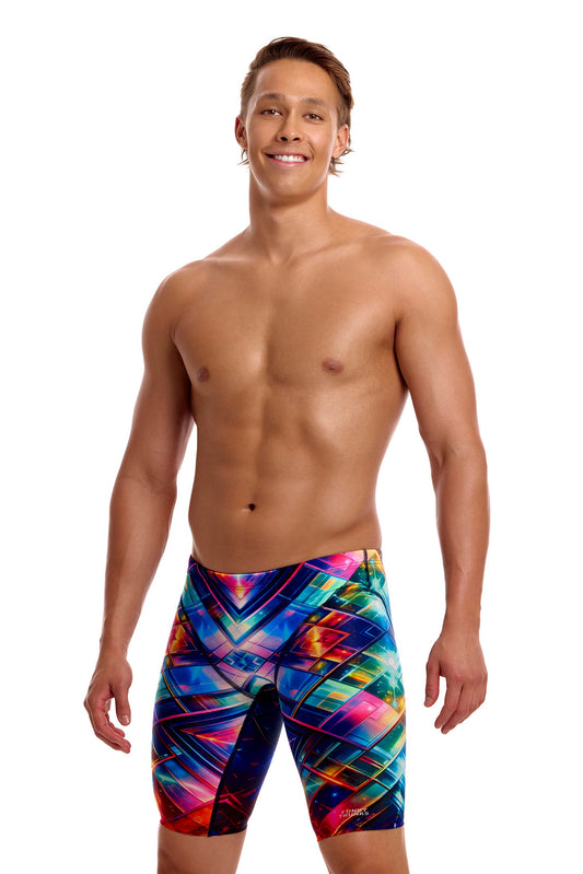 A male athlete standing against a solid white background modeling the Funky Trunks "Firefly Sparkle" Men's Fast Training Jammers, featuring a multi-colored geometric pattern across the swim jammers.