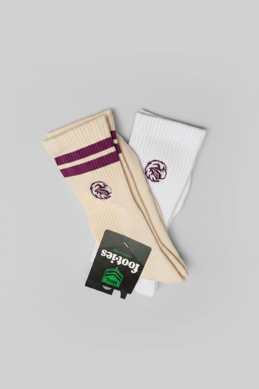 Two pairs of Footies crew socks, one cream with purple stripes and embroidered Sea Eagles logo, and one white with a purple logo.