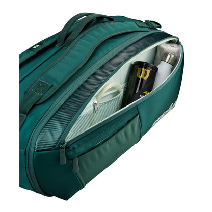 Open accessory compartment of green Wilson Blade V10 bag holding a tennis ball tube, bottle and towel.
