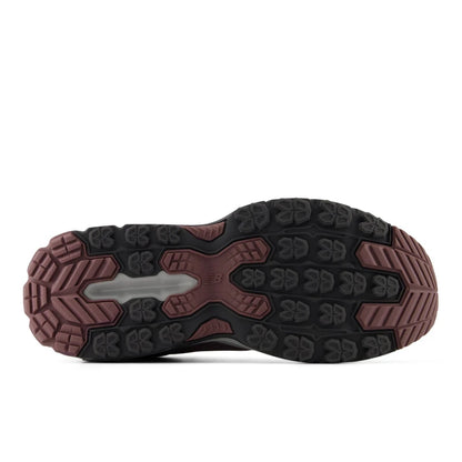 Bottom view of the rubber outsole on the New Balance Women's 410v9 trail running shoe, displaying black and dusty rose-pink multi-directional traction lugs against a light grey background.
