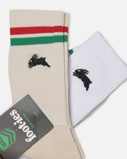 Two crew socks from Footies by Nike, one in beige with red and green stripes and a black rabbit logo, and one in white with a black rabbit logo, displayed with a product tag.