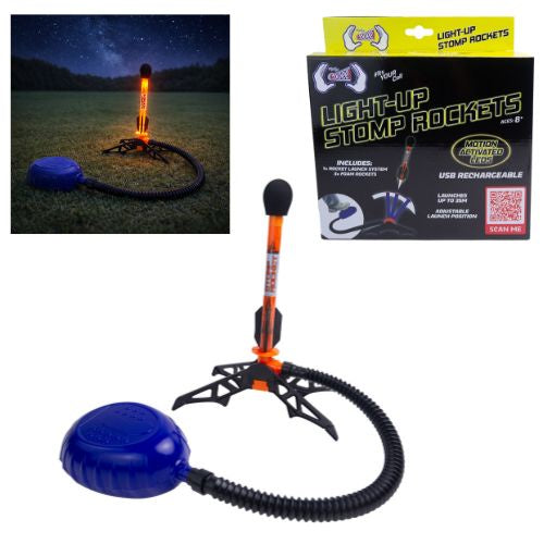 A light-up stomp rocket toy shown on a white background with its retail box, plus a small inset photo demonstrating the rocket lit up outdoors at night. The product includes a blue pump reservoir, black stomp base, orange rocket body, and glowing orange flame effect.