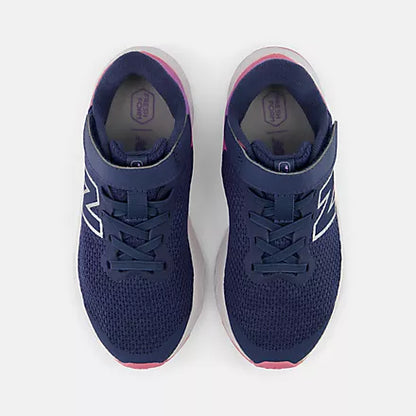 Top view of New Balance Kids Arishi v4 Hook & Loop running shoes in vintage indigo blue placed side-by-side, featuring bungee laces, pink heel trim, and dark purple-blue mesh uppers against a light grey background.
