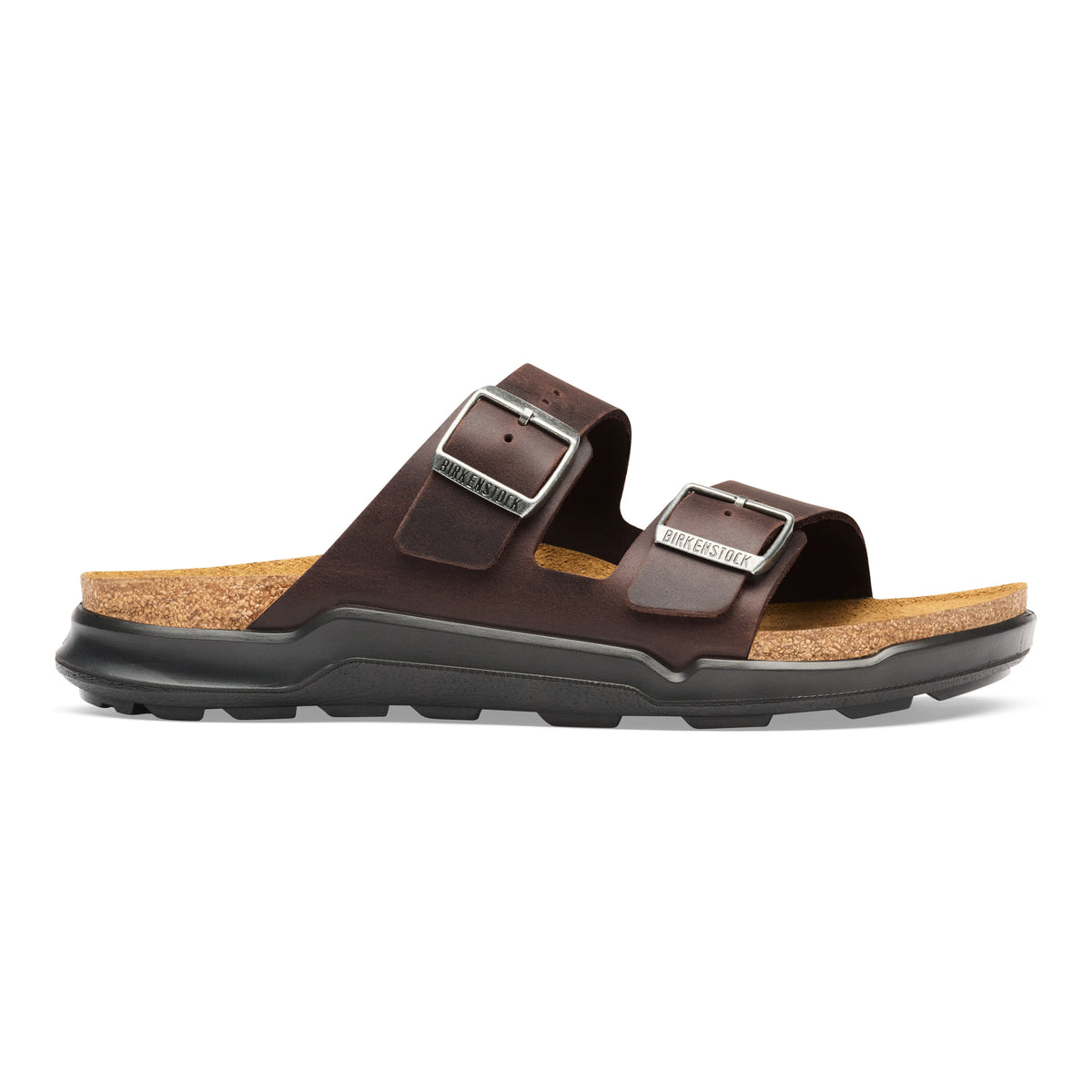 A dark brown double-strap leather slide sandal with silver-tone metal buckles, a cork-textured footbed, and a black rubber sole, shown in profile against a white background.